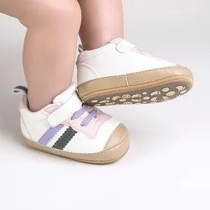 Dettaglio scarpe primi passi per neonati con suole antiscivolo morbide.
