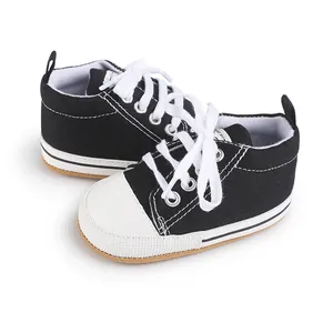 Detalle de zapatillas de lona negra para bebé con cordones blancos y puntera blanca