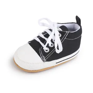 Detalle de zapato de lona negro para bebés con cordones blancos y puntera blanca