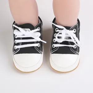 Close-up detailed view of black and white baby canvas sneakers with secure white shoelaces