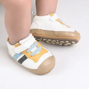 Primo piano di scarpine bianche per neonati con dettagli gialli e blu ai piedi di un bimbo