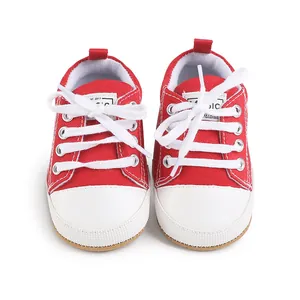 Close-up view of red canvas baby walker shoes with white rubber toes and cotton laces.
