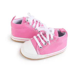 Detalle de los zapatos de lona rosa para bebé con cordones blancos para niños de 0-1 año.