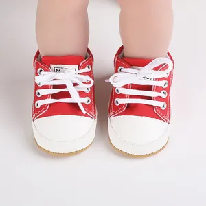 Close-up of red and white infant walking shoes with lace-up canvas design.