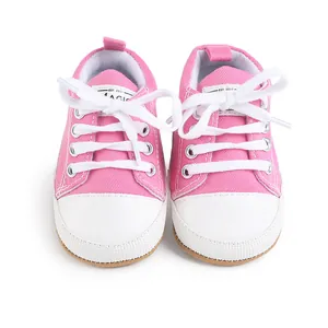 Adorables zapatos de lona rosa para bebés con cordones blancos y suelas blandas.