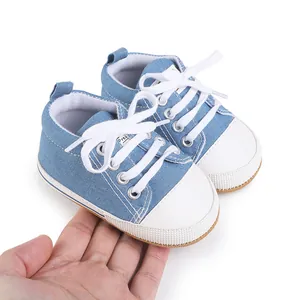 Detailed view of blue baby canvas sneakers held by hand to showcase the compact size.