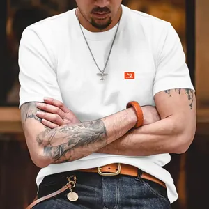 Primer plano de una camiseta blanca ajustada para hombre con un pequeño logo naranja en el bolsillo.