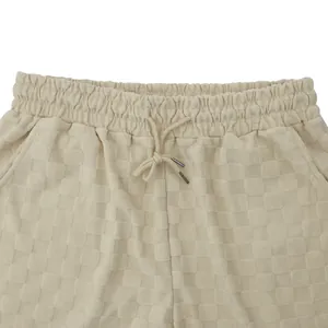 Close-up of beige jacquard checkered shorts with elastic drawstring waistband and textured fabric