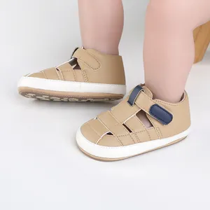 Close-up of tan baby walking shoes with navy blue straps and white soles