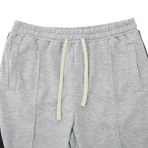 Detail view of grey sweatpants featuring drawstring waist and side stripe detail