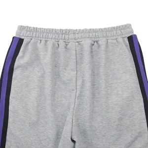 Close-up detail of gray men's sports trousers featuring purple and black side stripes