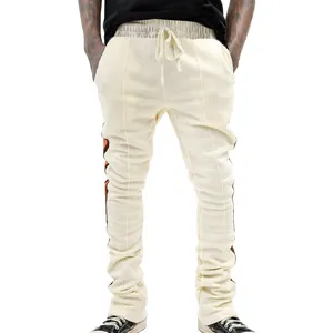 Detailed view of men's cream stacked joggers featuring decorative side stripes and drawstring.