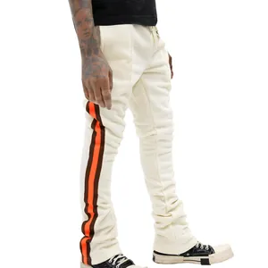 Zijaanzicht detail van de crème stacked sweatpants voor heren met oranje zijstrepen