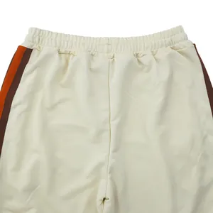 Detail of cream men's joggers showing elastic waist and orange-brown side stripes
