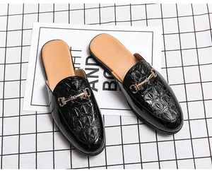 Détail macro de mules en cuir de crocodile noir véritable avec boucle dorée