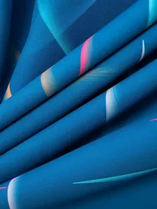 Macro detail of high-quality blue fabric with colorful abstract feather patterns for men's shirt.