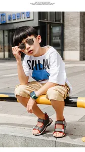 Sandalias de exterior grises y rojas para niños con correas de velcro en un entorno urbano.