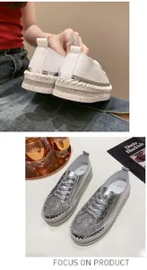 Close-up view of silver platform sneakers with rhinestone toes and white lace-up design