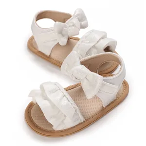 Detailed view of white glittery baby sandals featuring elegant ruffle and bow accents