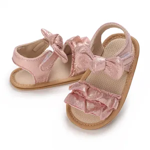 Detail view of pink glittery baby sandals featuring decorative bows and ruffles