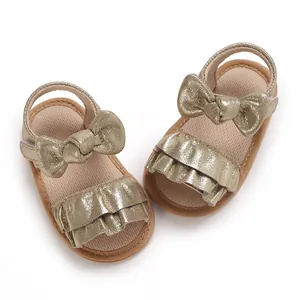 Close-up detail of golden metallic baby sandals with ruffled bow accents