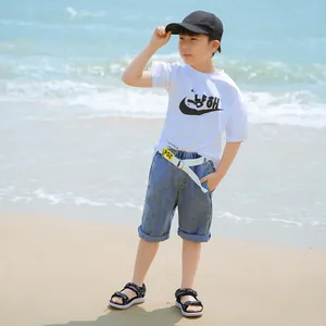 Close-up of a boy wearing black lightweight casual beach sandals on a sunny sandy shore.