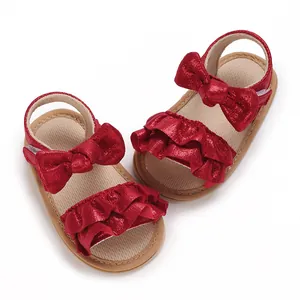 Detailed overhead shot of red metallic baby sandals featuring bows and ruffles for summer