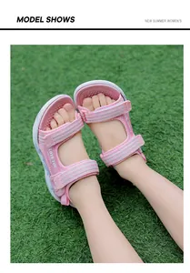 Detail view of girls' pink summer sandals with velcro straps on green grass