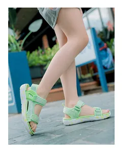 Close-up of a child wearing light green soft-sole summer sandals on stone pavement