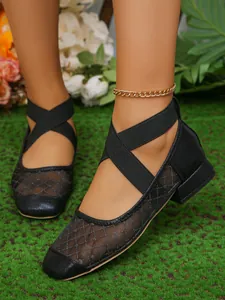 Primo piano di eleganti ballerine nere in mesh con punta quadrata e cinturini incrociati