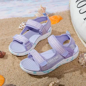 Purple girls beach sandals with soft soles and heart patterns on sandy background