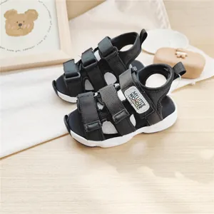 Primo piano di sandali sportivi neri per bambini con cinturini in velcro su legno.