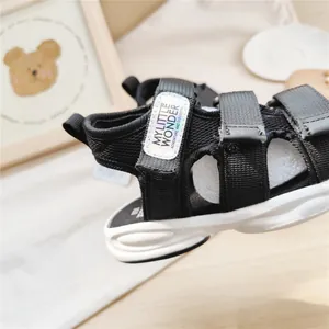 Dettaglio di sandali sportivi neri per bambini con suole bianche e velcro.