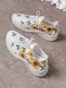 Detailansicht weißer Mesh-Sneaker mit lebhaften Sonnenblumen- und Schmetterlingsdrucken.