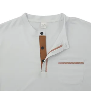 Close-up of white polo shirt with brown button placket and chest pocket detail