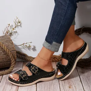 Detailed side view of black crocodile pattern wedge sandals with ornate metal buckles.
