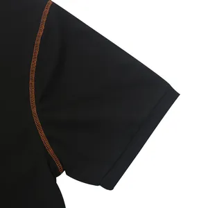 Detailed close-up showing orange contrast stitching on the sleeve of a black polo shirt