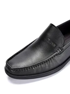 Gros plan d'un mocassin en cuir noir montrant le grain et le logo embossé de la marque