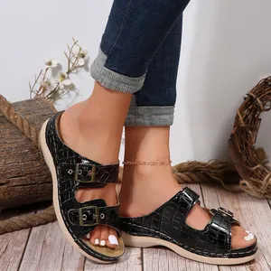 Detailed view of black crocodile-textured double-buckle wedge sandals on a model