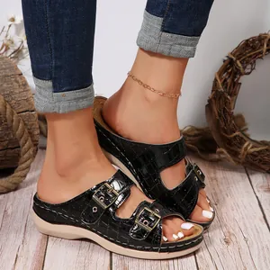 Close-up of women's black crocodile texture wedge sandals with double gold buckles