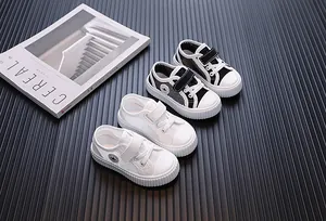 Top view of white and black breathable mesh toddler sneakers on dark background