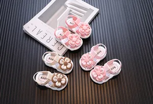 Detailed view of baby girl flower sandals on dark ribbed background with magazine prop