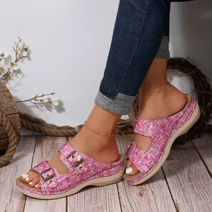 Close-up of women's pink grid wedge sandals with metal buckles for summer wear.