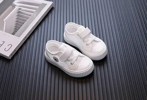 Detailed view showing breathable mesh texture and velcro strap on white children sneakers