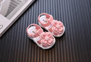 Macro detail of pink baby sandals featuring large decorative 3D flowers and soft white soles