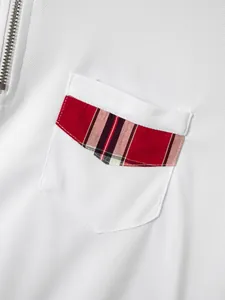 Detailaufnahme eines weißen Poloshirts mit roter karierter Tasche und Metallreißverschluss.