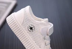 Close-up of white breathable mesh children sneaker with velcro strap and star patch