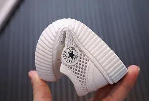Flexible white mesh toddler shoe detail showing soft sole and star patch