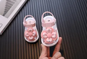 Detail of pink baby sandals with a large flower decoration and closed-toe design
