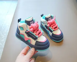 Detalle de zapatillas altas de colores para niños con cordones rosas gruesos y suela azul.